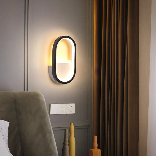 Elegante 'LuceMuraleModerna' Wandlampe in Weiß/Schwarz, die ein sanftes, warmes Licht abgibt, montiert an einer grauen Wand neben einem Vorhang.